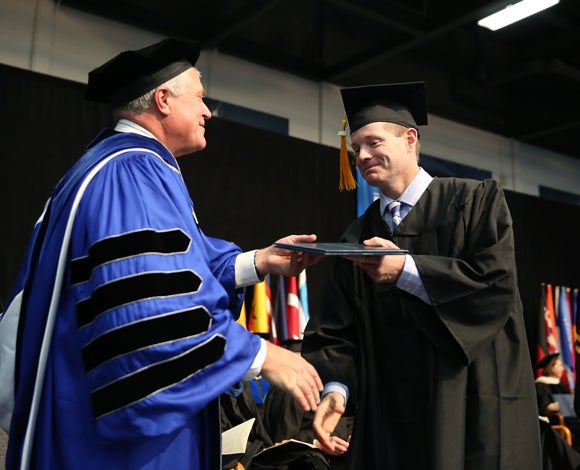 Melvin Winberg receives his diploma Dec. 16 from Chancellor Bob Meyer during commencement at UW-Stout. Winberg spent parts of 17 years working toward his degree.