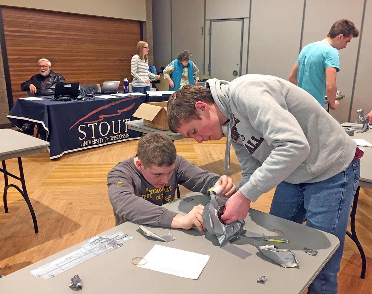 Menomonie High School students Ben Ehlert, at left, and John Kluge build a catapult from drinking straws, rubber bands and duct tape at Stout Expo during the state Wisconsin Science Olympiad tournament