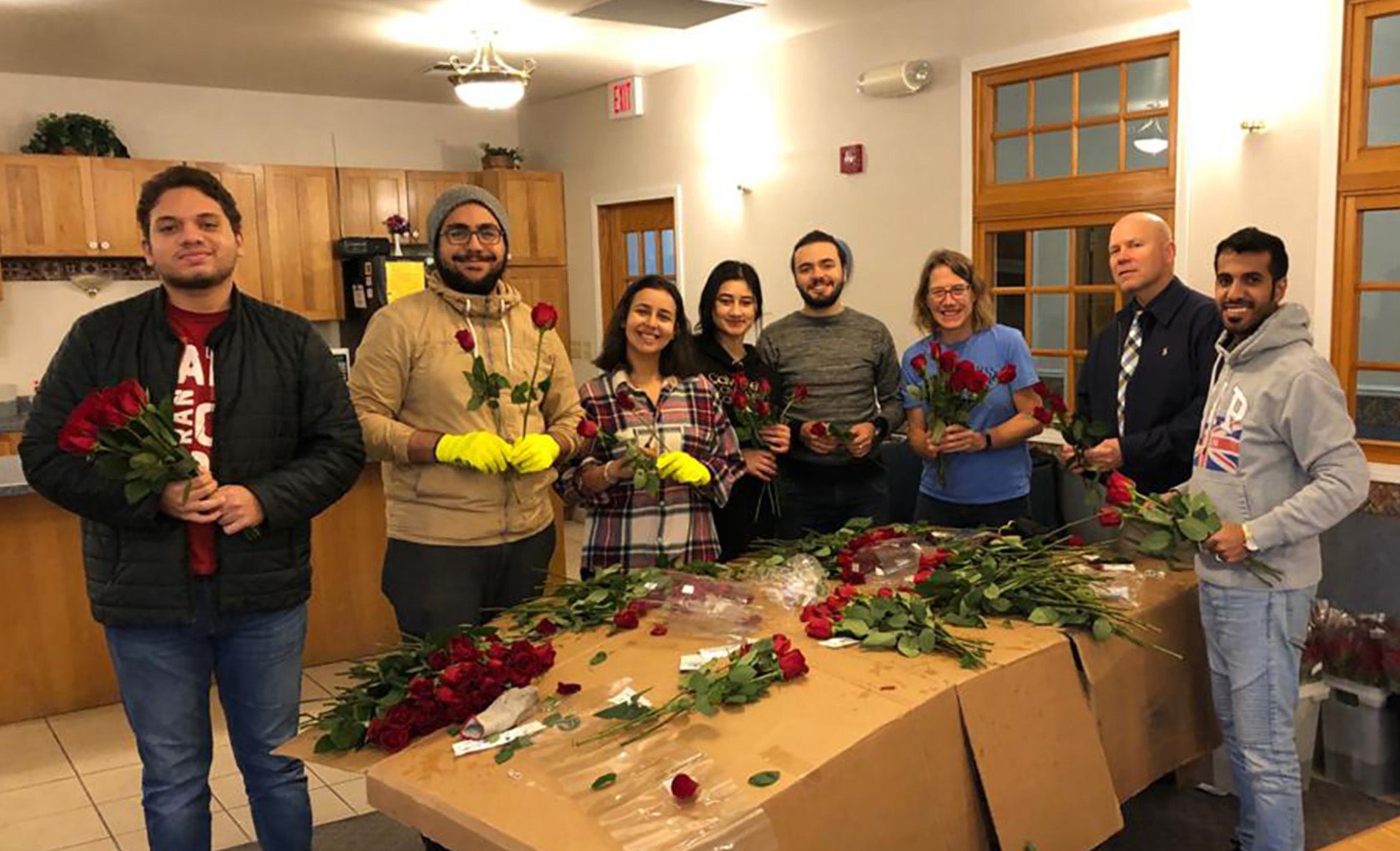 International students at UW-Stout can qualify for a scholarship, which includes community service. Helping the Rotary Club of Menomonie deliver roses to raise money for service projects are Fedi Soltani, second from left; Nilu Omarova, fourth from left; and Sulaiman Alharbi, right.