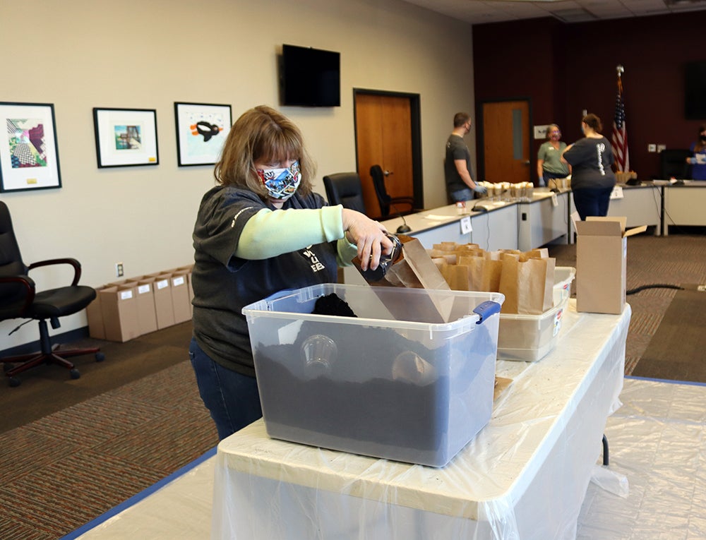 Xcel Energy employee Pam Taylor pours potting soil into brown bags for the kits.