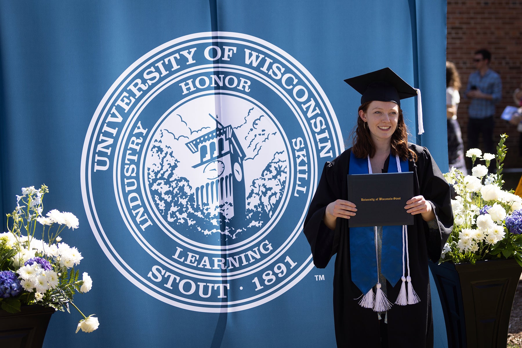 A student proudly displays her diploma during the spring 2022 commencement at UW-Stout.