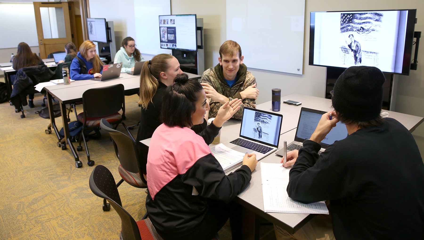 Students congregate around a computer discussing American politics.