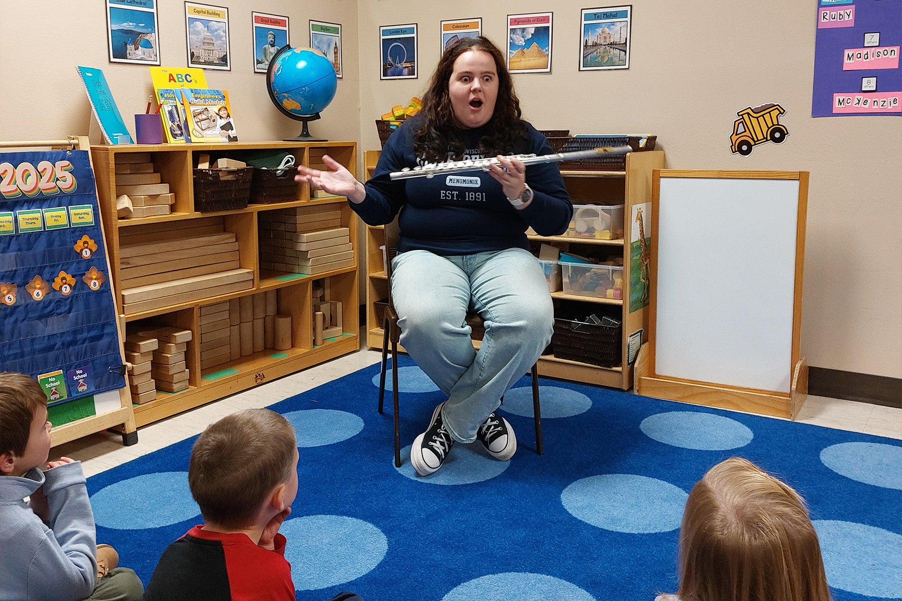 A Symphony Band student plays their flute for preschool students at the Child and Family Study Center
