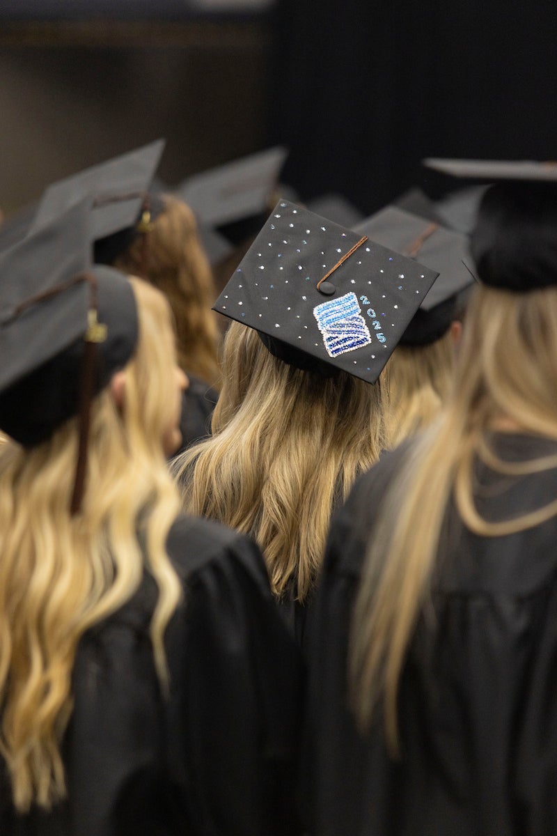 A student has decorated their cap with Stout's logo