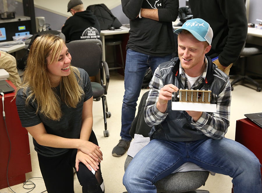 Beth Rocque, at left, and Drew Pearson, both technology education majors, talk over a quick fix on their bot Legendary White Ram made using a 3D printer.