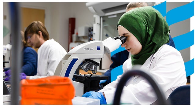 Student performs hands-on, applied learning with industry-standard microscope in science lab.