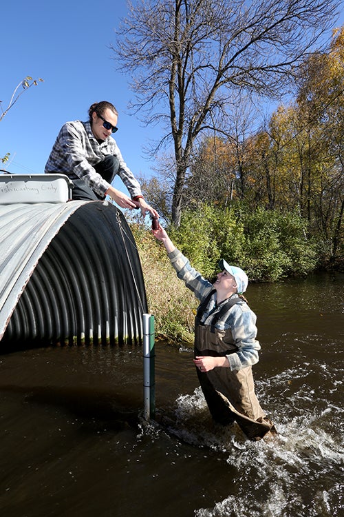 Heidi Lieffort, at right, associate research specialist with CLRR, hands water samples from Horse Creek to UW-Stout graduate student Conor Dougherty.