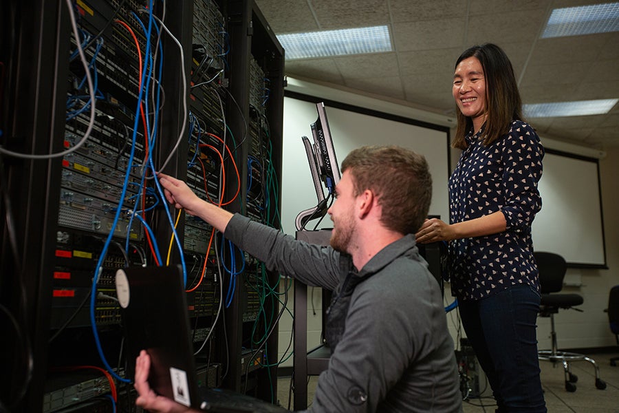 Holly Yuan, director of the Center of Academic Excellence in Cyber Defense at UW-Stout, said the Wisconsin and Minnesota College Cybersecurity Symposium is the first of its kind in the area. Yuan, at right, is working with a computer networking and information technology student in a class.