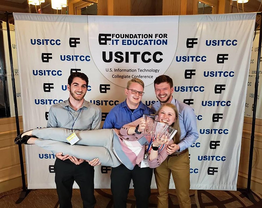 Nikki Ruf holds UW-Stout’s awards from the national information technology competition in Texas. From left are fellow students Luke Bednar, Karl Carey and Derek Muck.