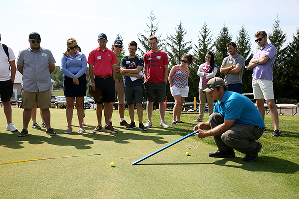 Tanglewood Greens Superintendent Jordan Hill uses a stimpmeter to measure the speed of the greens as UW-Stout students look on.