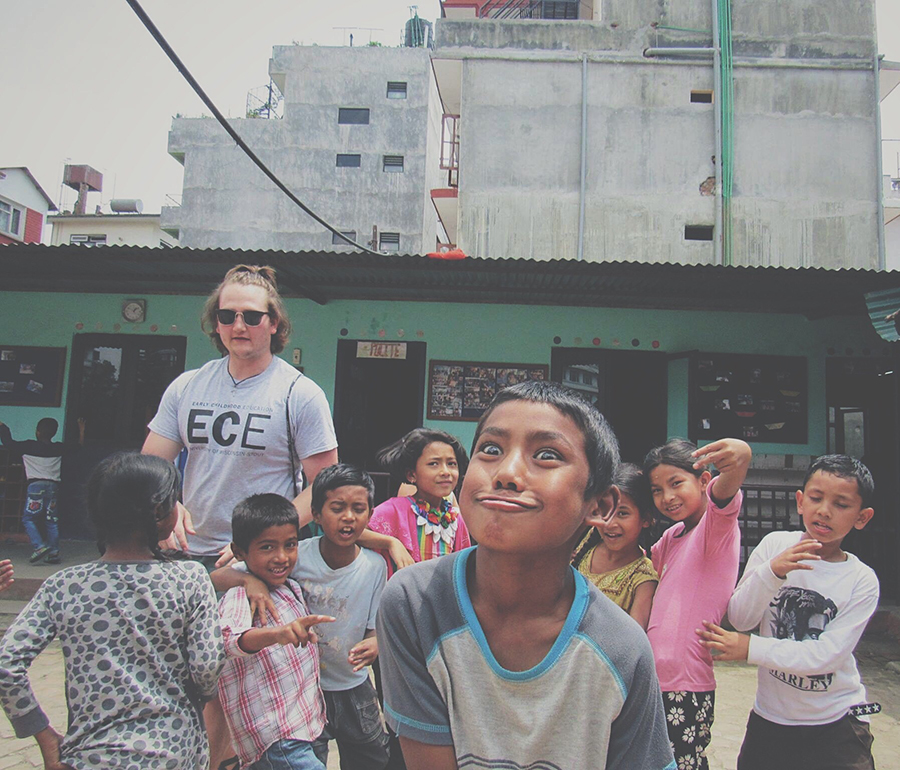 Lubs, pictured in a playground area with students, visited Nepal and taught there for a month. He encourages others to study abroad and learn about other cultures.