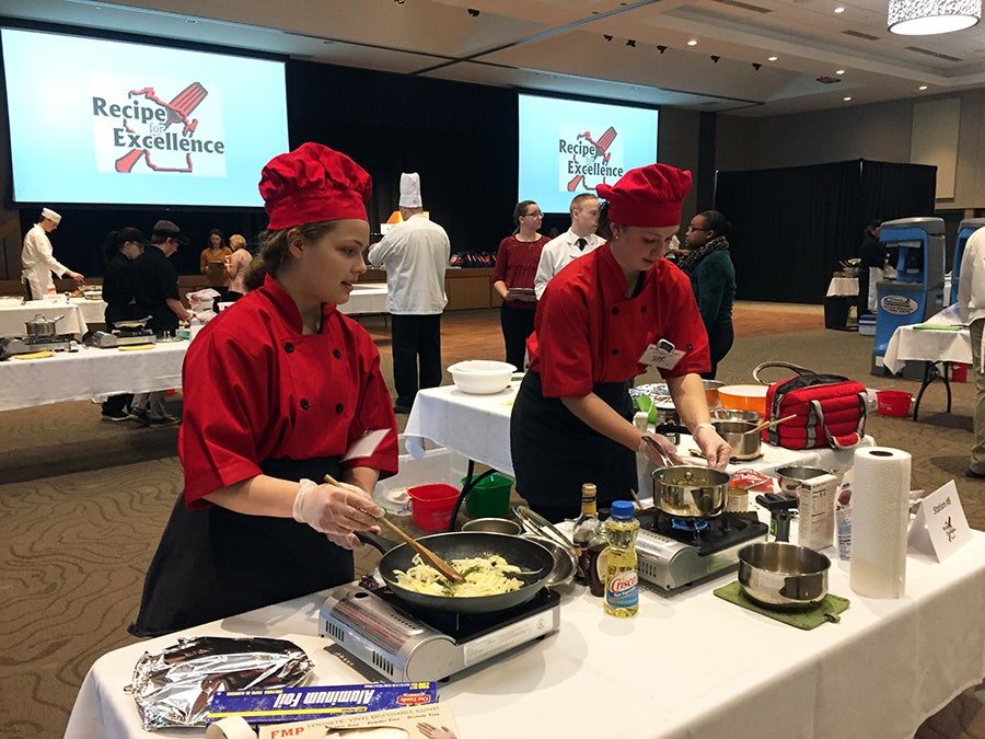 Luck High School student Rose King,  at left, stirs vegetables for a glazed pork chop dish in the Recipe for Excellence at UW-Stout with teammate McKenna Delany. / UW-Stout photos by Pam Powers