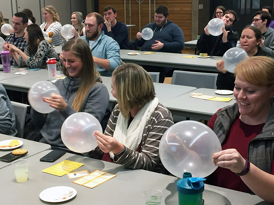 ​    ​UW-Stout graduate students Molly Borman, Harly VanBrunt and Jessica Boston laugh as they twirl a penny in an inflated balloon. All three agreed Olson was an engaging speaker with ideas how future counselors can connect with their students.