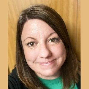 Rachel Siegersma is a white woman with straight, shoulder length brown hair. She is wearing a green shirt and standing in front of a wooden background.