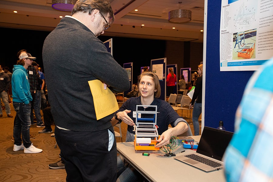 A student explains research on a standup wheelchair to Chuck Bomar, dean of the College of Science, Technology, Engineering, Mathematics and Management.
