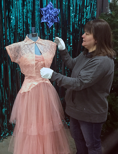 ​​Sofi Doane, collections manager for the Dunn County Historical Society, prepares a dress for a vintage clothing exhibit at the Snow Ball.