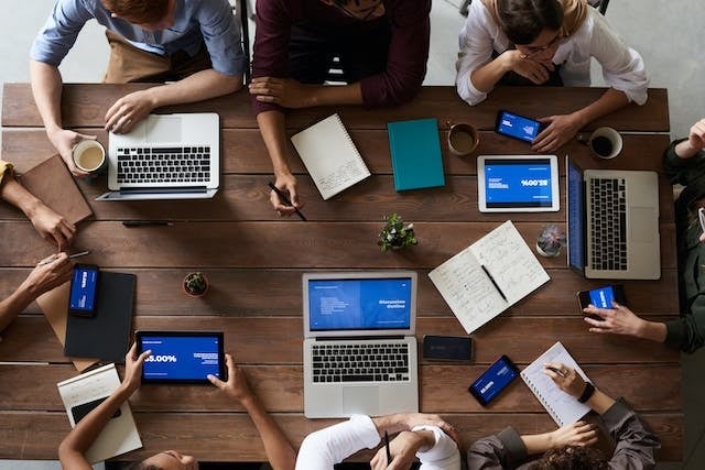 people sitting around a table with laptops open