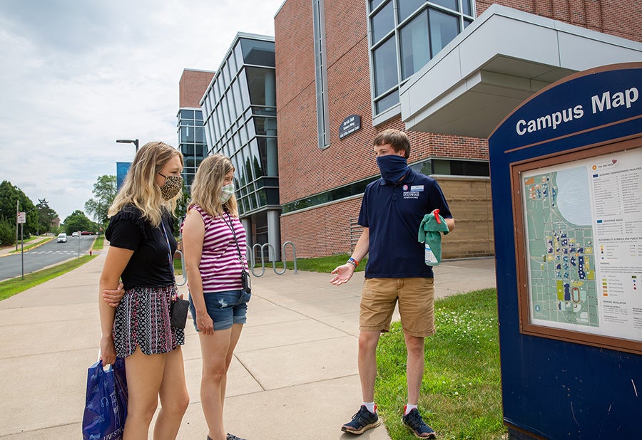 An Admissions Office guide wears a mask and carries sanitizer spray while conducting a tour for new students at UW-Stout.