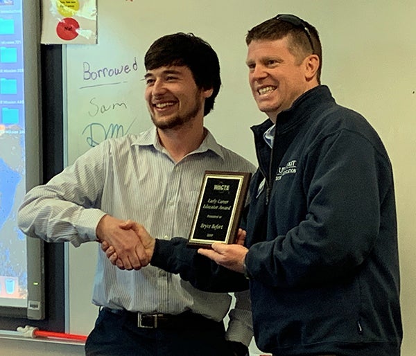 UW-Stout alumnus Bryce Befort, left, receives the WACTE Early Career Educator award recently in his sixth-grade classroom at Menomonie Middle School.