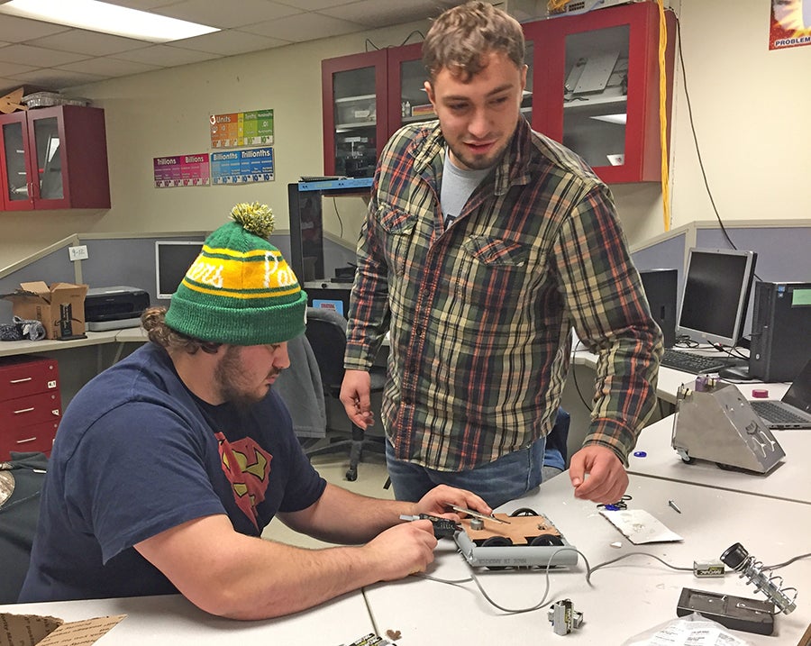 Students Dexter Shipley, at left, and Eli School repair their bot the Scorpion, which went on to win the Mechatronics 371 class competition. PVC pipe as bumpers made the bot strong and light.