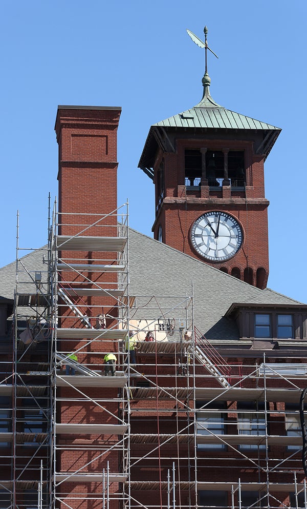 Workers on scaffolding repair the south side of Bowman Hall.