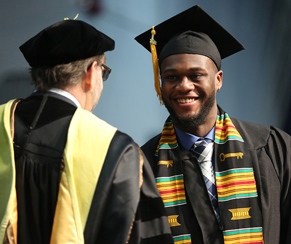A graduate is congratulated while crossing the stage at commencement in December 2018.
