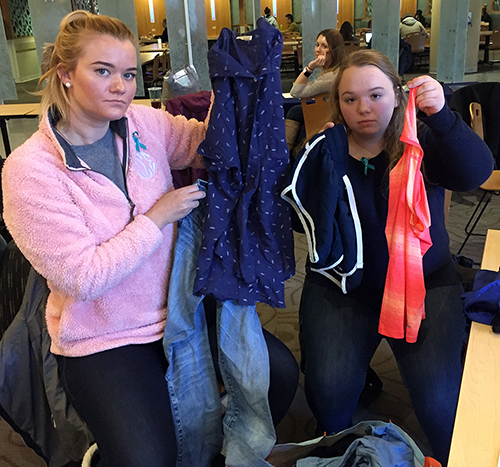 UW-Stout students Jessi Weber, at left, and Ellie McKee, show some of the clothing that was on display in April at the Memorial Student Center as part of a survivor art installation entitled “What Were You Wearing.” The clothing matched descriptions sexual assault survivors reported they were wearing at the time of the assaults.