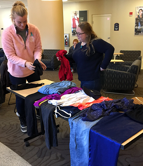 ​​UW-Stout students Jessi Weber, at left, and Ellie McKee, sort through some of the clothing that is on display at the Memorial Student Center as part of a survivor art installation entitled “What Were You Wearing.” The installation is part of a weeklong events by the Students for Consent group that includes a skit and panel discussion.