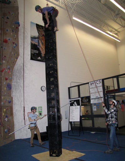Student Devon Manuele stands on about 20 of the eventual 23 milk crates he stacked while harnessed during a competition at Stout Adventures. The free event encourages students to try climbing. 