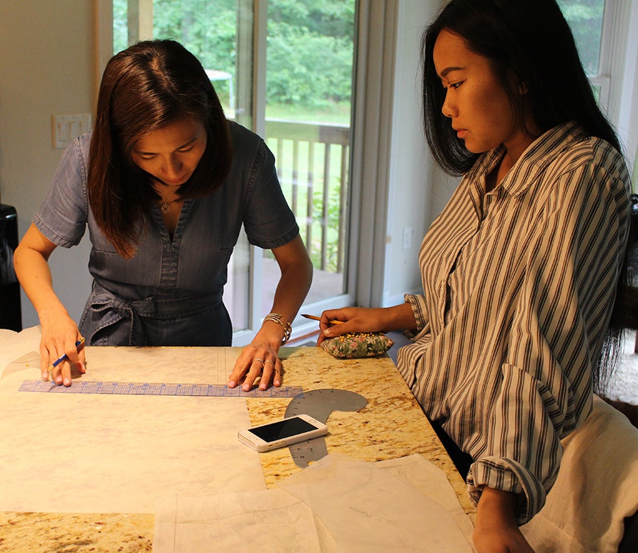 Ngo works on a design with Nkao Hle Hang, a volunteer at Cross Border Wear, a sophomore at UW-Stout studying apparel design and development.