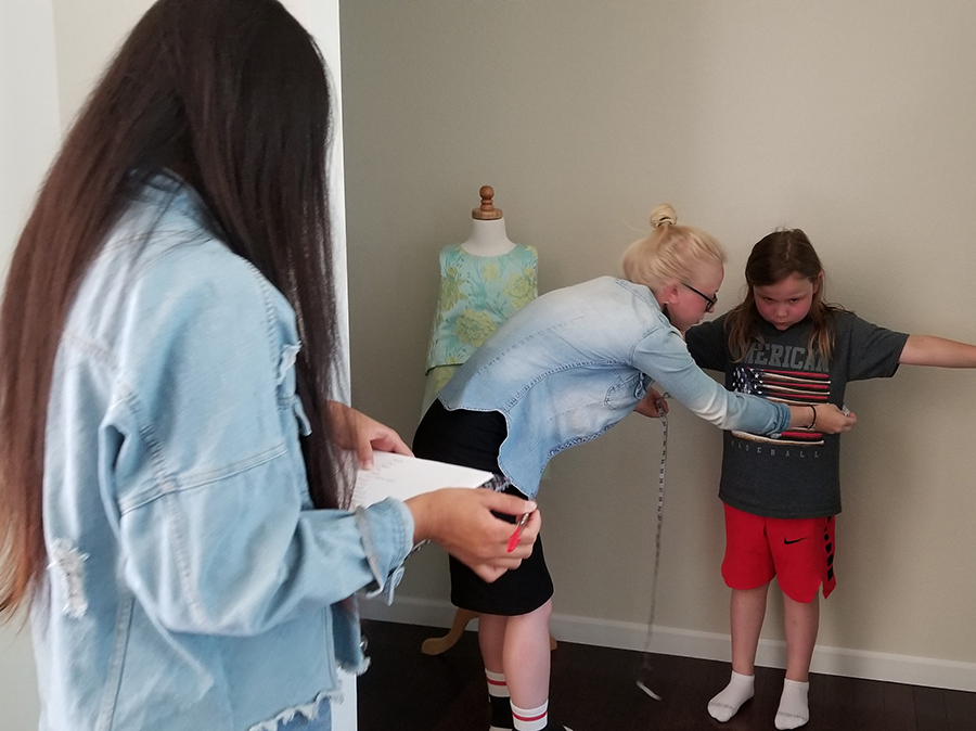 UW-Stout alumnus Isabel Korab takes measurements of one of the children who modeled Cross Border Wear’s clothing in a recent show.