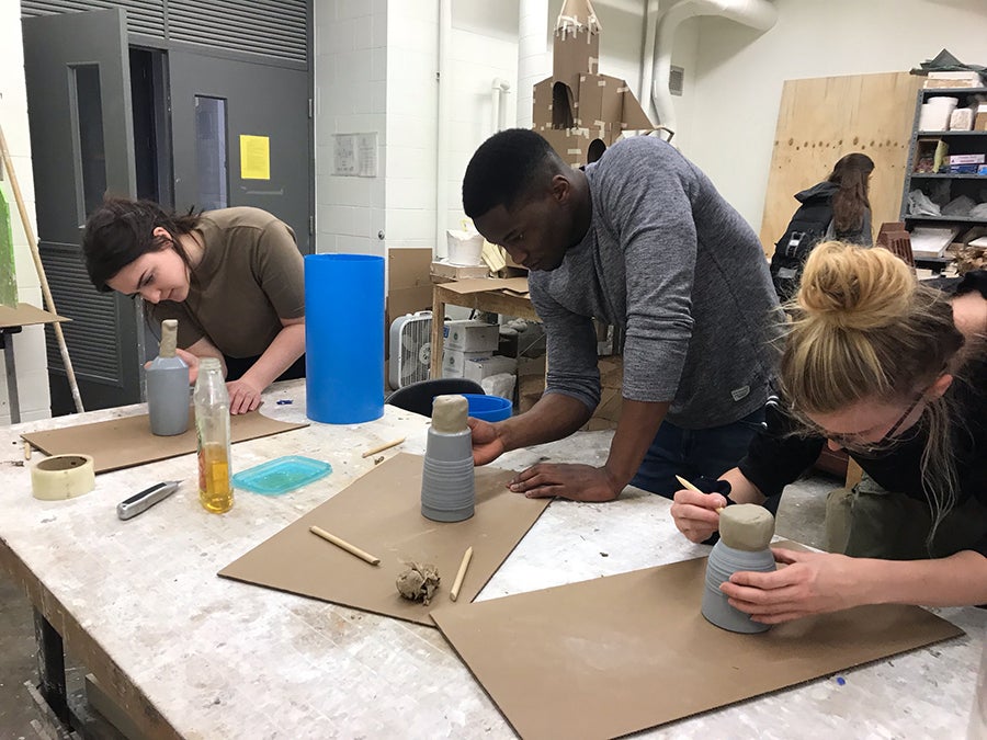 Students Angela Hastings, Obadiah Nyabuto and Isabel Case prep mug designs to make molds.