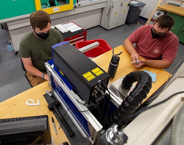 Senior engineering students Jake Thomas, left, and Deven McCarty work on Made at UW-Stout door pullers in the plastics engineering lab. Thomas designed the tool, being given to first-year students, and McCarty helped engineer it.