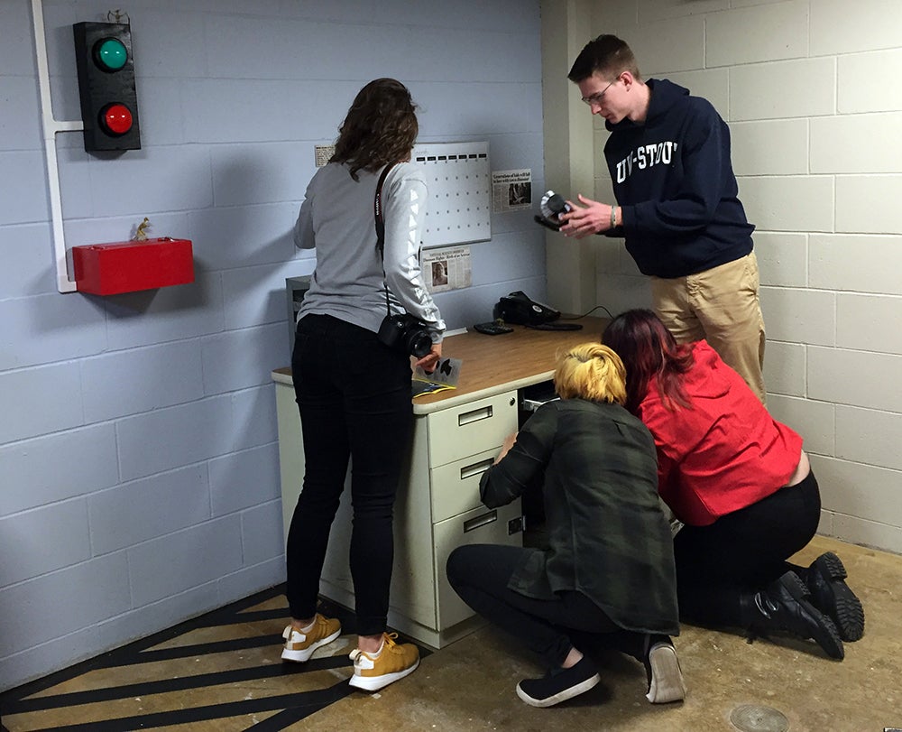 Team members, left to right, Nicole Juza, Theresa Hang, Chia Lor and Sam Giesregen, search for clues in the Jurassic Stout escape room.