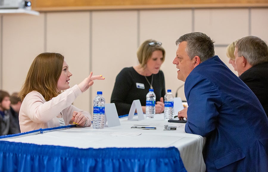 Alumnus Justin Holley talks with a student after the panel discussion.