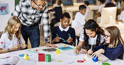 Teacher helping students with math project.