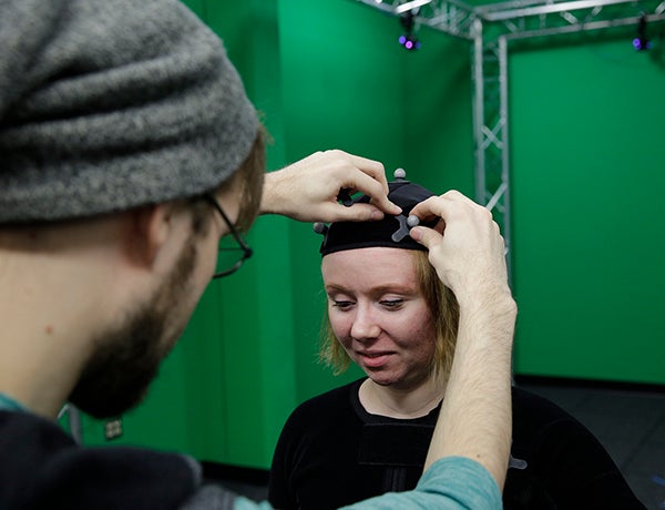 Andrew Fedie adjusts a reflector on the motion capture suit worn by Danielle Pedersen.