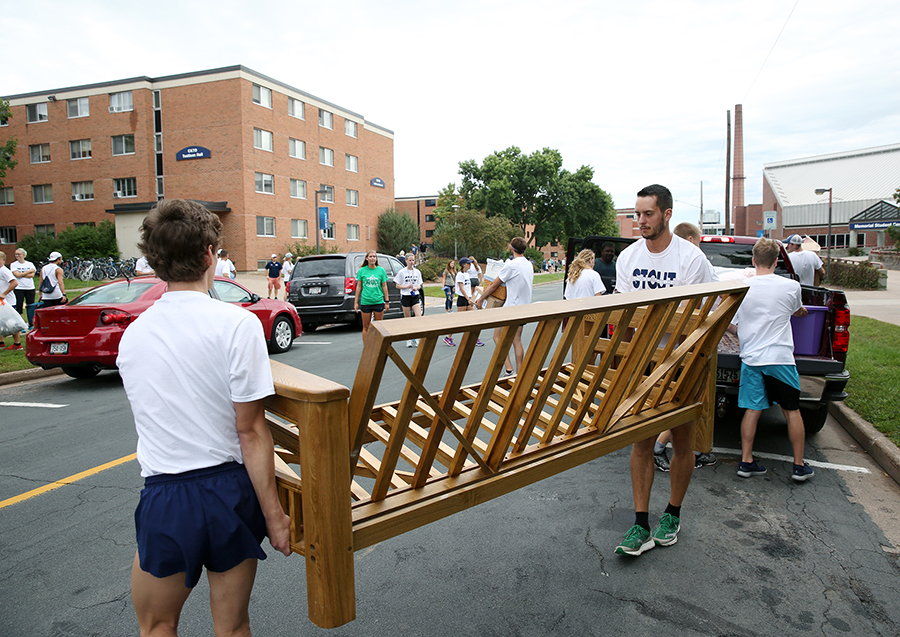 Athletes help a new student move a futon frame into a residence hall in 2018.