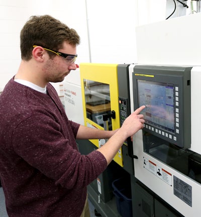 Plastics engineering major Bennett Conrardy programs a machine in the plastics engineering lab at UW-Stout.