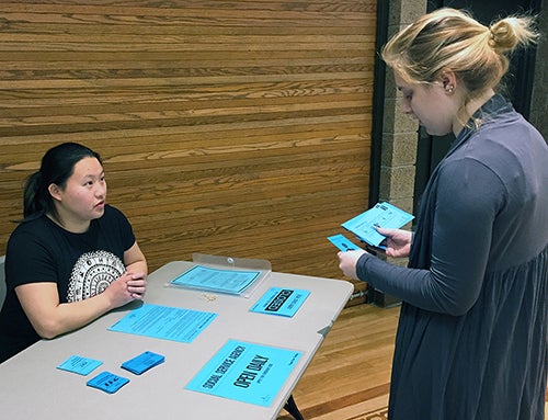 Rebecca Silberfarb, a UW-Stout student, at right, questions fellow student, Maiyee Vang, about possible social service agency funding during a hunger and poverty simulation.