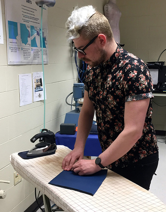 Brandon Schmidt, a junior in apparel design and development, presses some of the art smocks as part of one of his classes.