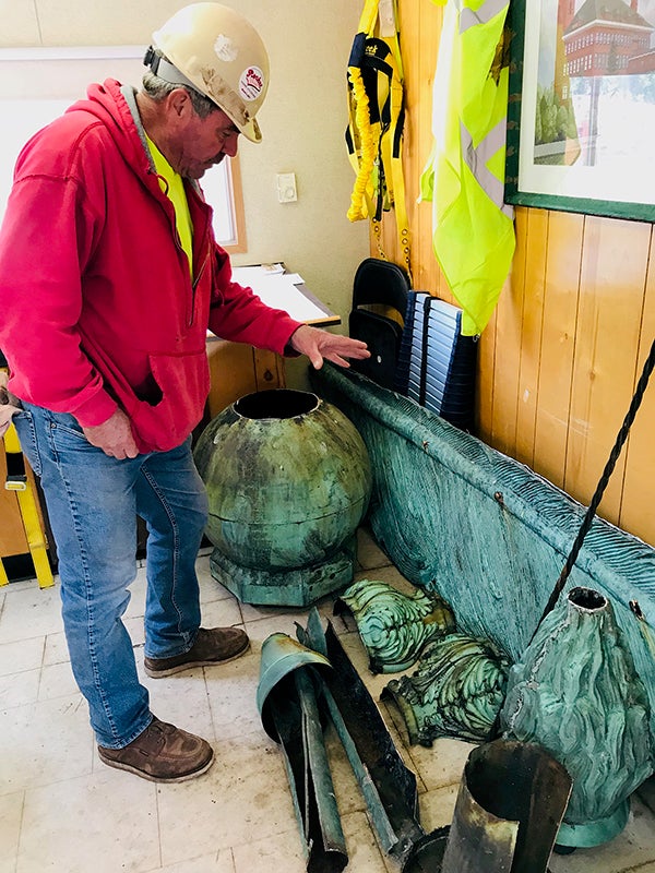 Joe Vaughan, Building Restoration Corp. foreman for the Bowman Hall project at UW-Stout, views the quill, torch and other parts, which will be restored or replaced.