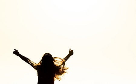 Silhouette of woman raising her hands