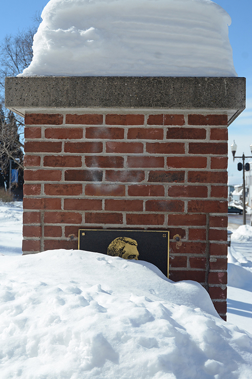Snow is piled up to the eyes of a plaque honoring James Huff Stout, the founder of UW-Stout.