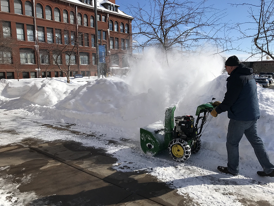 Zenon Smolarek, associate director of Facilities Management, uses a snowblower to widen a sidewalk near Bowman Hall.