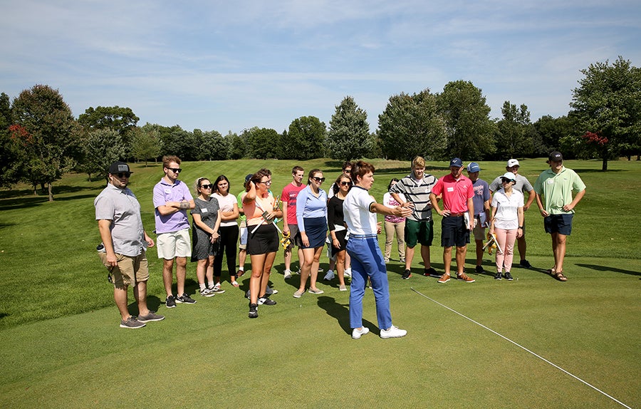 A Sports Event Management class listens to Associate Professor Kris Schoonover at Tanglewood Greens, where the Tees Fore Tuition event will be held.