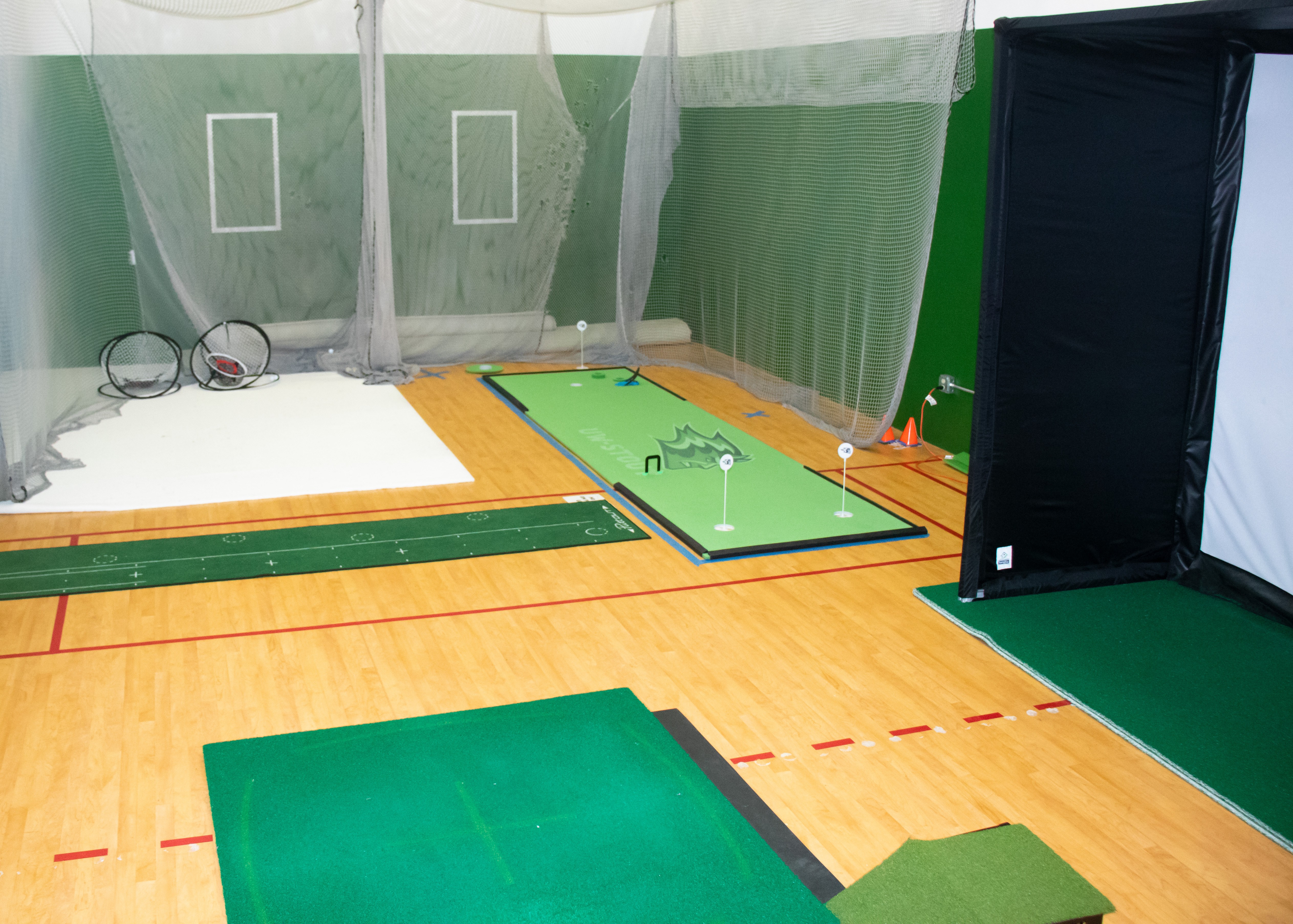 Photo illustrating the layout of golf room with driving range, putting green and golf simulator.