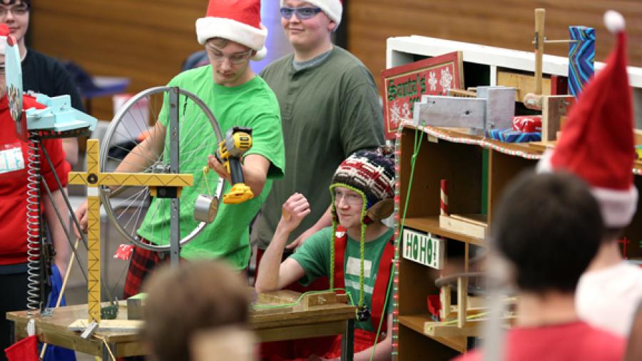 Elk Mound High School student Tanner Stockdill, as Ralph the Elf, shows a bandage on the back of his hand after the team’s Rube Goldberg machine Santa’s Workshop finished a run Monday, March, 20, at UW-Stout. Elk Mound won the regional competition.