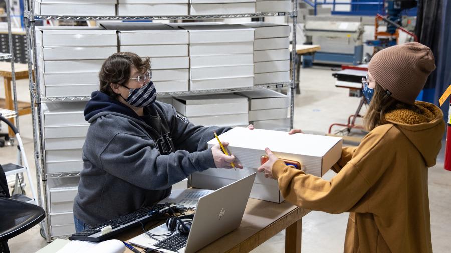 Cathie Weissman, UW-Stout School of Art and Design staff member, hands out a kit to a student in the 3D Design Foundations class.
