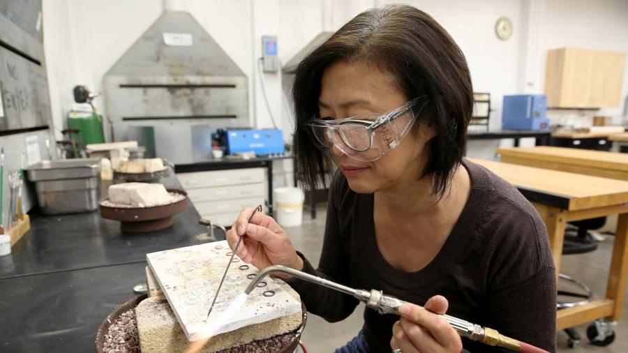 Professor Masako Onodera creates a pin in the arts metal lab in 2016.